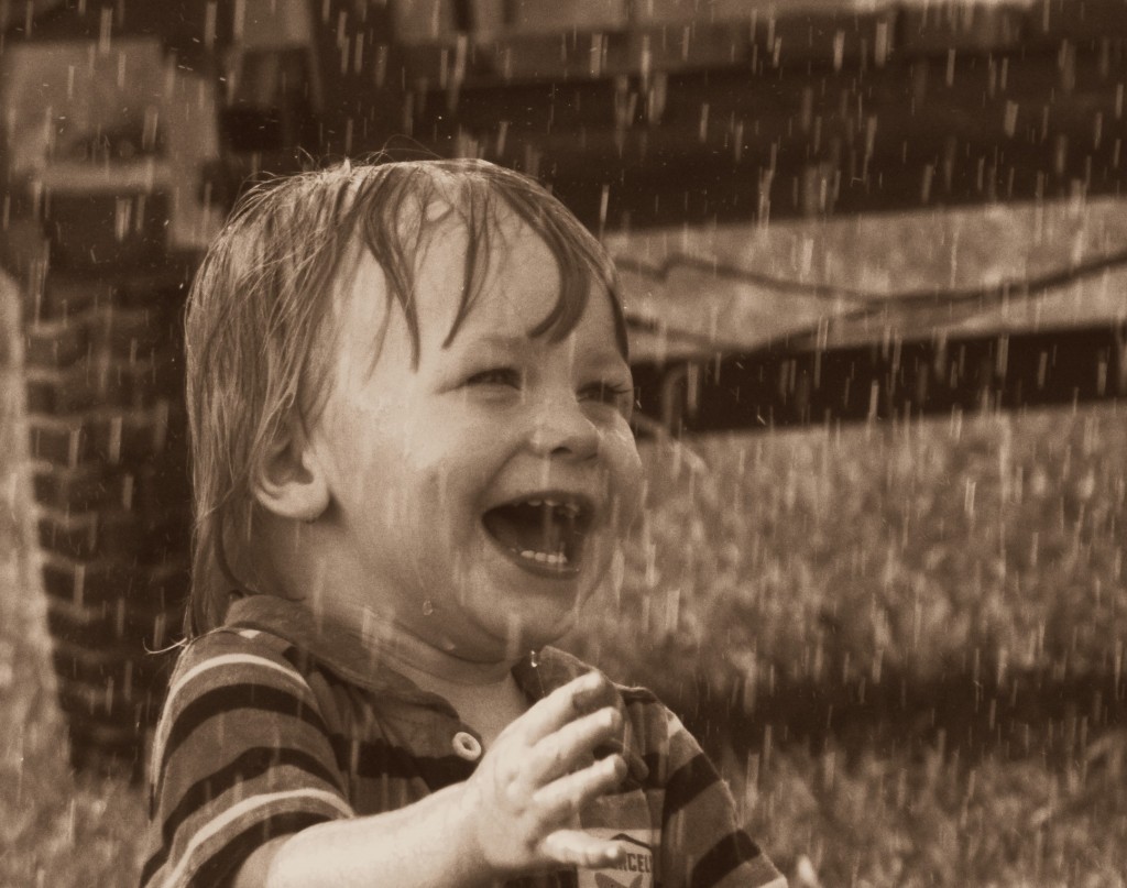 A toddler laughing in the rain.